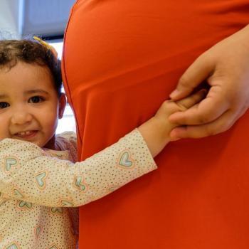 Fillette enlaçant une femme enceinte