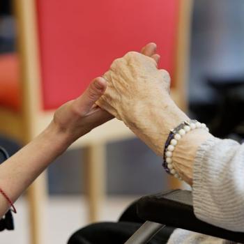 Aidant et personne âgée se tenant la main
