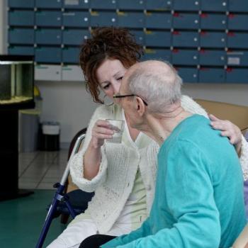 Soignant dans un EHPAD, donnant de l'eau à une personne âgée